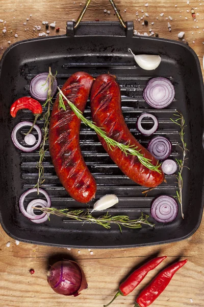 Ahşap arka plan üzerinde bir tavada ızgara sosis