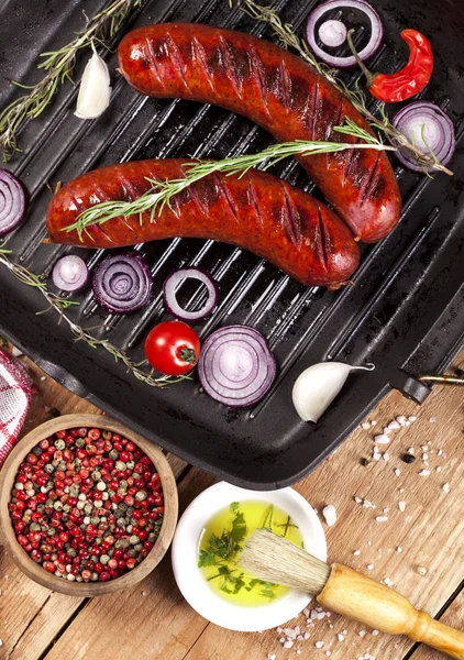 Ahşap arka plan üzerinde bir tavada ızgara sosis