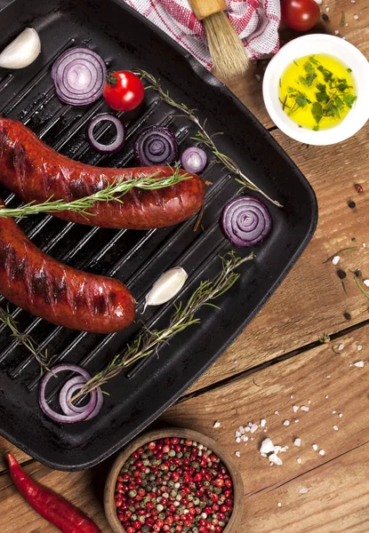 Ahşap arka plan üzerinde bir tavada ızgara sosis