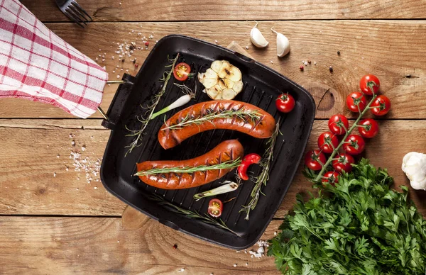 Ahşap arka plan üzerinde bir tavada ızgara sosis