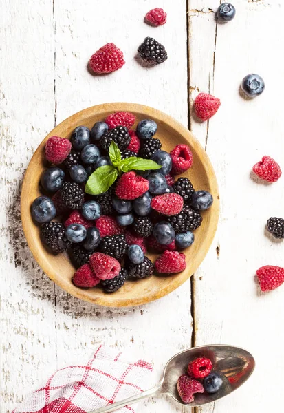 Ahşap beyaz zemin üzerine kabın içinde olgunlaşmış ve tatlı çilek