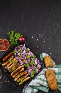 Soğan ve maydanoz siyah arka plan üzerine bir tavada kızarmış sosis