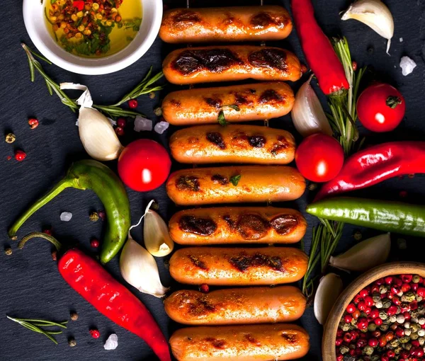 Otlar, baharatlar ve sebzeler siyah arka plan üzerine Kızarmış sosis