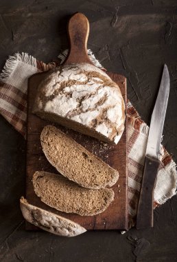 Geleneksel ekmek dilimlenmiş ve karanlık bir masada.