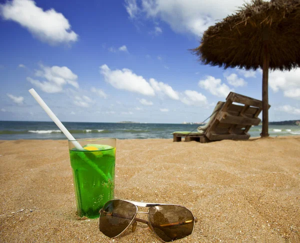 水の近くの黄金の砂のビーチで緑のアルコールカクテル — ストック写真