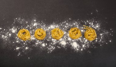 Siyah taş arka planda İtalyan geleneksel çiğ makarnası, üst manzara.