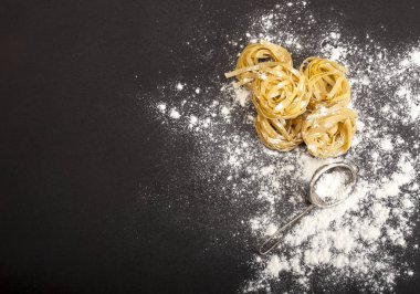 Siyah taş arka planda İtalyan geleneksel çiğ makarnası, üst manzara.