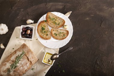 Beyaz peçetede zeytinyağı, zeytin, sarımsak ve otla dilimlenmiş geleneksel tost ekmeği.