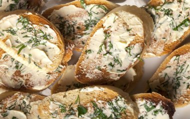 Beyaz tabakta tereyağlı, sarımsaklı ve otlu geleneksel tost ekmeği.