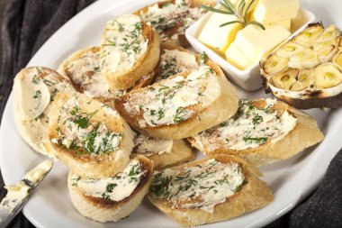 Beyaz tabakta tereyağlı, sarımsaklı ve otlu geleneksel tost ekmeği.