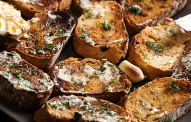 Kahverengi tabakta tereyağlı, sarımsaklı ve otlu geleneksel tost ekmeği.