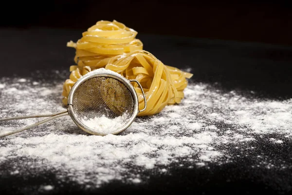 Pasta cruda tradicional italiana en el fondo de piedra negra — Foto de Stock