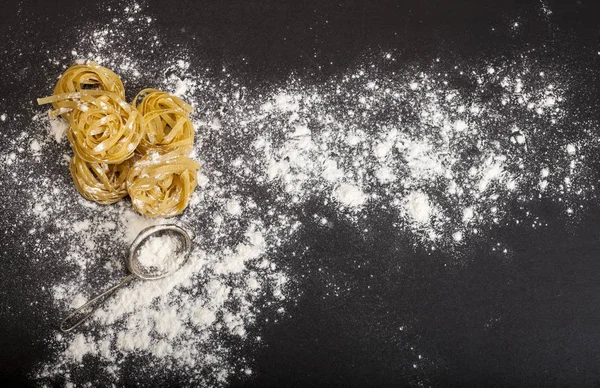 Italienische traditionelle rohe Pasta auf schwarzem Stein-Hintergrund, Draufsicht — Stockfoto