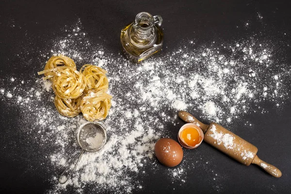 Italiaanse traditionele rauwe pasta op de zwarte stenen achtergrond, bovenaanzicht — Stockfoto