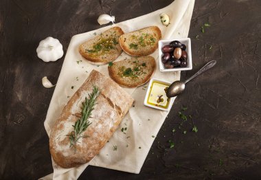 Beyaz peçetede zeytinyağı, zeytin, sarımsak ve otla dilimlenmiş geleneksel tost ekmeği.