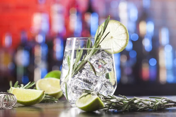 Glass with alcoholic drink with lime, ice and rosemary — Stock Photo, Image
