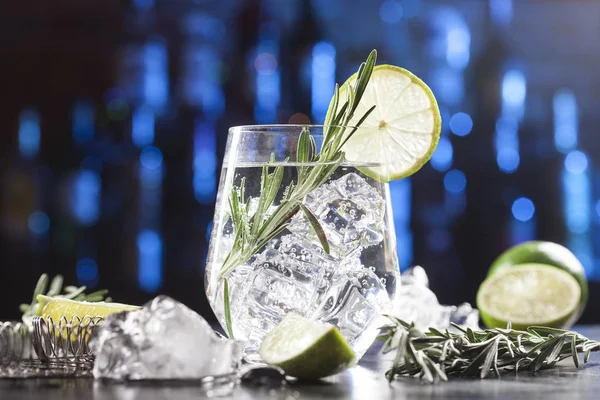 Glass with alcoholic drink with lime, ice and rosemary — Stock Photo, Image