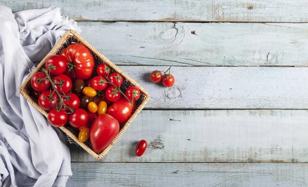 Tomaten op rustieke blauwe houten achtergrond bovenaanzicht kopieerruimte. — Stockfoto