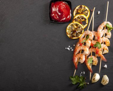 Limonlu karides, sarımsak ve siyah arka planda otlar. Kopyalama alanı olan üst görünüm.