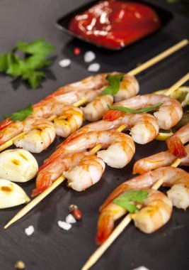 Limonlu karides, sarımsak ve siyah arka planda otlar. Yakın çekim.