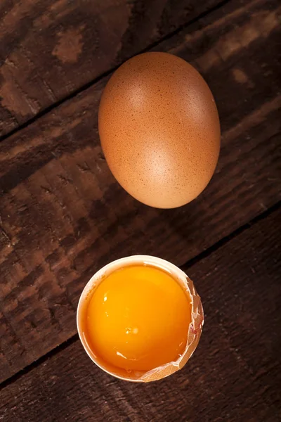 Bruin ei en gebroken ei met dooier op rustieke tafel. — Stockfoto