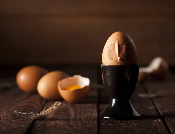 Bruine eieren en gebroken ei met dooier op rustieke tafel. — Stockfoto