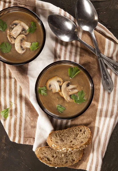 Delicious creamy mushroom soup with parsley and close-up on a dark background.