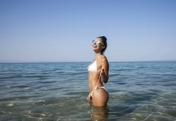 若いですブルネット女性で白い水着日光浴に海の海岸. — ストック写真