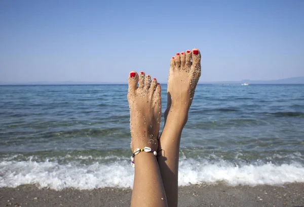 Kvinnliga solbrända ben på sandstranden. Resekoncept. Lyckliga fötter i ett tropiskt paradis. — Stockfoto