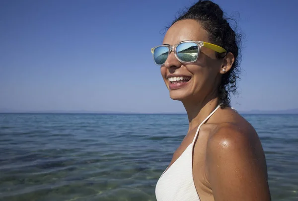 सफेद तैराकी सूट में युवा ब्रुनेट महिला समुद्र तट पर धूप स्नान . — स्टॉक फ़ोटो, इमेज