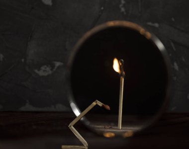 Kırık kibrit aynaya karşı ve yansıma tüm yanan çubuğu gösteriyor.