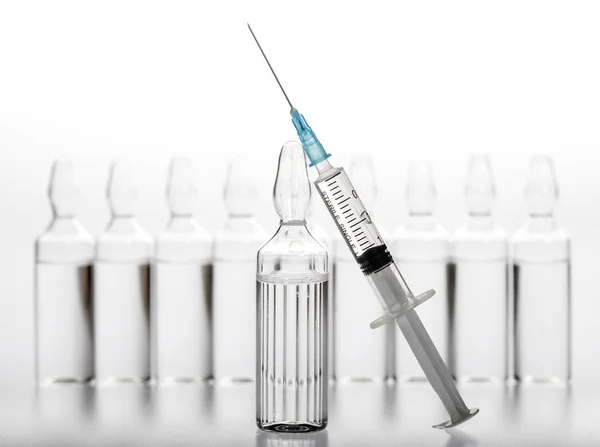 Ampolas de medicina de vidro e seringa no fundo branco — Fotografia de Stock