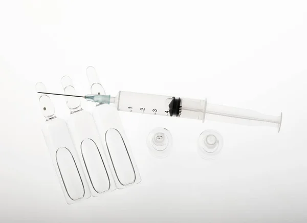 白色背景下的玻璃药液和注射器 — 图库照片