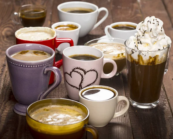 Lotes de café em copos diferentes em mesa de madeira — Fotografia de Stock
