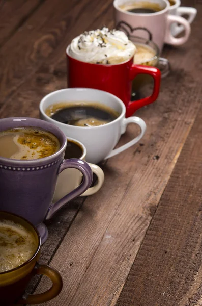 Lots of coffee in different cups on wooden table — Stock Photo, Image