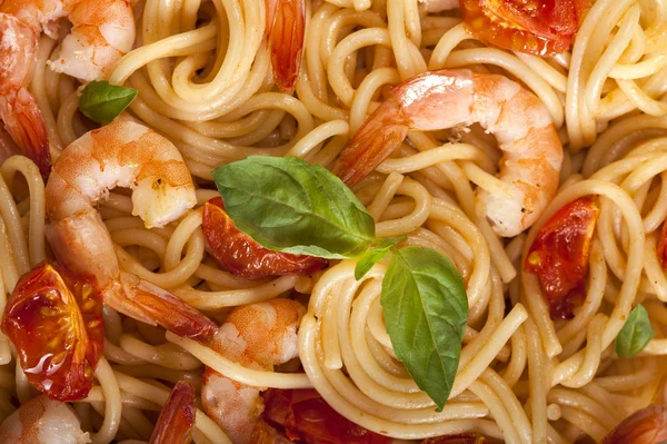 Nudelspaghetti mit Garnelen, getrockneten Tomaten und Basilikum in Nahaufnahme. Gesundes Essen. Italienische Lebensmittel. — Stockfoto