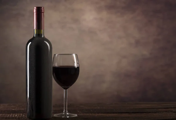 Rotwein in Glas und Flasche mit Staub auf dunklem Hintergrund mit Kopierraum — Stockfoto