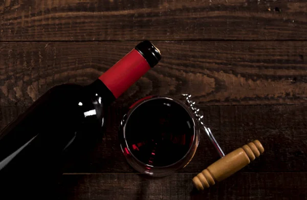 Červené víno ve skle a láhev na dřevěném pozadí s kopírovacím prostorem — Stock fotografie