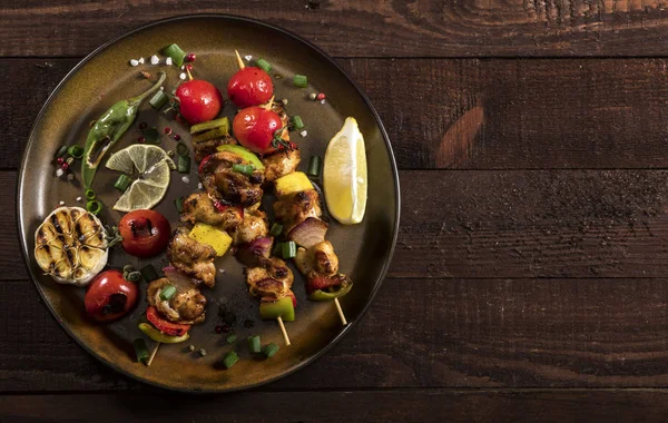 Grillade kyckling spett med kryddor och grönsaker i en panna på trä bakgrund — Stockfoto