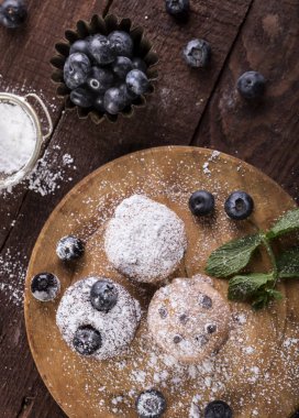 Ahşap arka planda yabanmersini ve çikolatalı kekler.