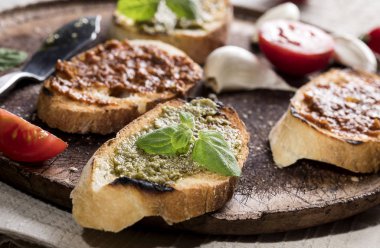 Geleneksel tost ekmeğini fesleğen ve domates pesto ile dilimlenmiş kesim tahtası ve beyaz masa.