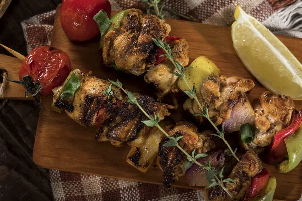 Brochettes de poulet grillées avec épices et légumes sur planche à découper et fond en bois — Photo