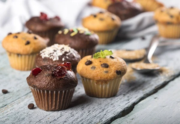Verschiedene frische leckere Muffins auf blauem Holzhintergrund — Stockfoto