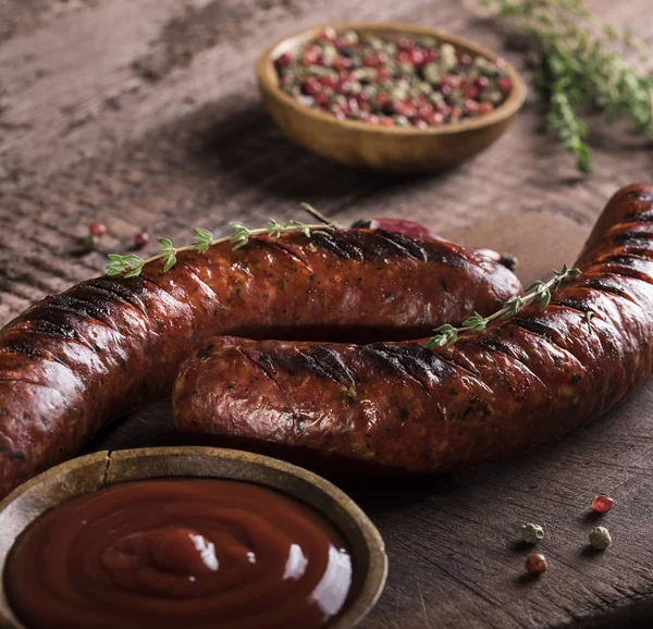 Grilled sausages on cutting board and wooden background — Stock Photo, Image