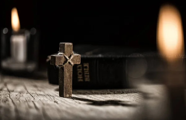 Holy Bible and wooden cross on dark background