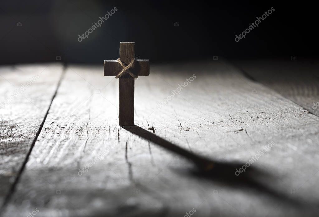 Wooden cross on dark background with copy space.