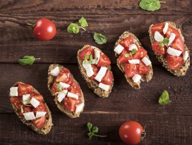 Domates, mozzarella peyniri ve ahşap kaplamalı fesleğen. Geleneksel İtalyan aperatifi veya aperatifi, antipasto. Üst Manzara. Düz yatıyordu