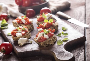 Domates, mozzarella peyniri ve ahşap kaplamalı fesleğen. Geleneksel İtalyan aperatifi veya aperatifi, antipasto..