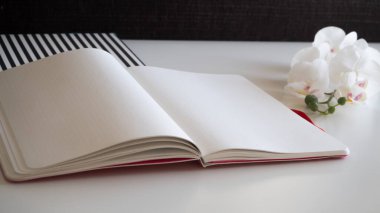 Beyaz masadaki defter kalem, orkide ve çizgili desen ile düzenlenmiş - köşegen kenar görünüm