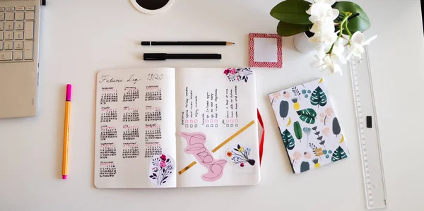 Journal style de vie, Bullet Journal - Planer - Notebook - vue de dessus avec des ustensiles disposés sur fond blanc, orchidée, crayons, notes collantes — Photo